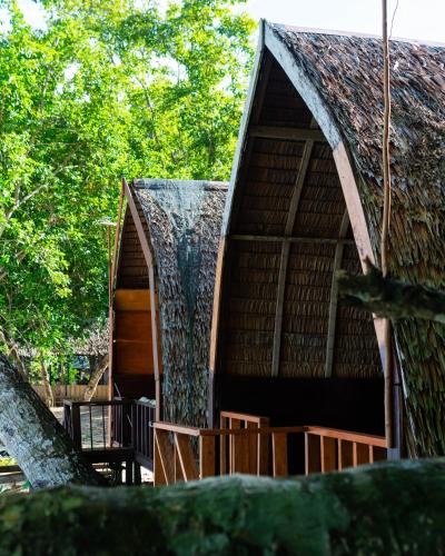a building with a thatched roof and a tree at Koridek Homestay in Friwin