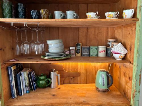 a wooden shelf with plates and cups and books at The Venus room at Glendower Homestead in Greytown