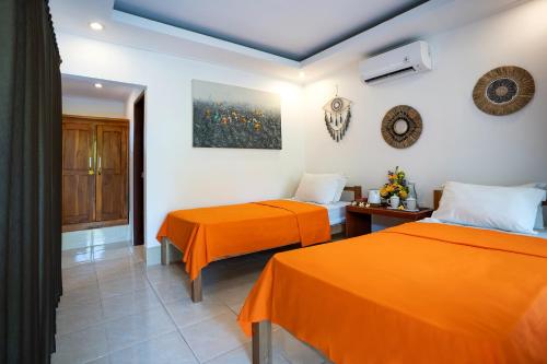 two beds in a room with orange sheets at Ganesh Beach Hotel in Candidasa