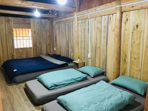 a bedroom with three beds and wooden walls at Lullaby Ha Giang Homestay in Loung Co