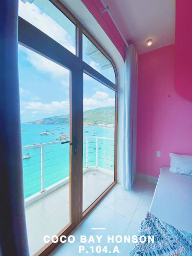 a bedroom with a large window with a view of the ocean at Coco Bay Hon Son in Lai Sơn