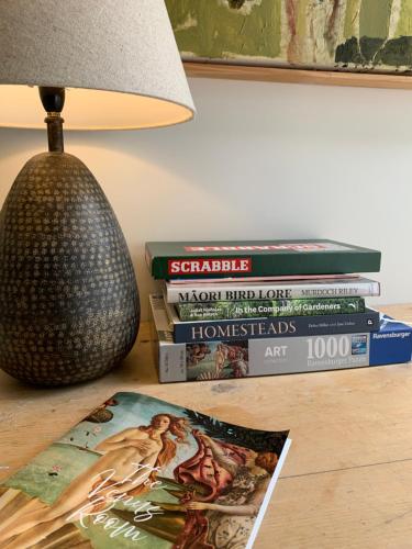 a stack of books sitting on a table next to a lamp at The Venus room at Glendower Homestead in Greytown