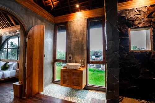 a bathroom with a sink in a room with windows at Villa Rabita in Ubud