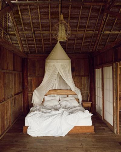 a bedroom with a white bed with a canopy at Vaikuntha Villa Bali in Selat
