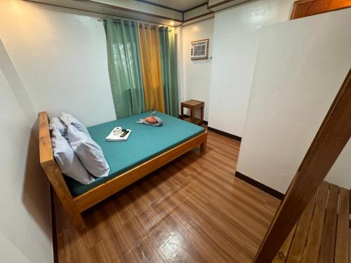 a room with a bed with a pillow and a pair of shoes at Nay Carmen Pension House Port Barton in Itaytay