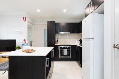 a kitchen with black cabinets and a white counter top at Smart Suites Self Check-in Apartments - W Freney in Brisbane