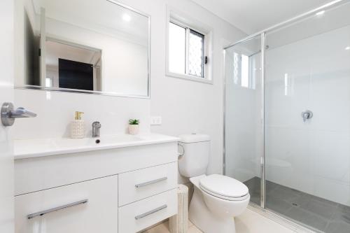 a white bathroom with a toilet and a shower at Smart Suites Self Check-in Apartments - W Freney in Brisbane