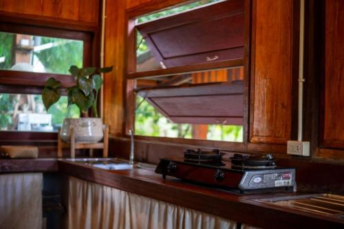 a kitchen counter with a stove and a window at Hug Bolaven Homestay and Camping in Ban Nongpèn