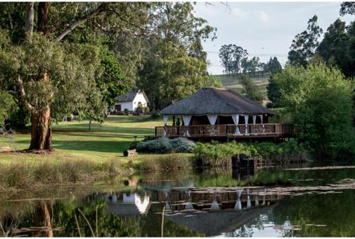 a gazebo with a roof next to a lake at The Retreat Country Lodge in Romelcoh