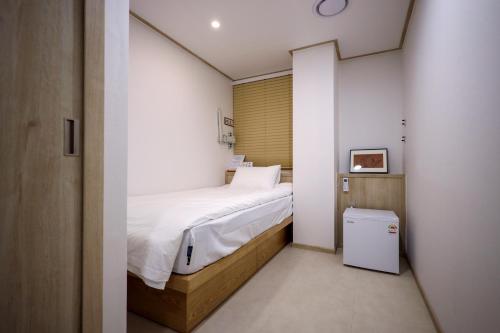 a small bedroom with a bed and a small refrigerator at Manso Hostel in DDP in Seoul