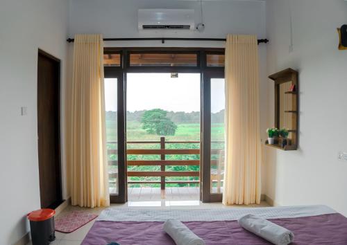 a bedroom with a bed and a sliding glass door at Wilpattu Restaurant & Guest house in Pahala Maragahawewa