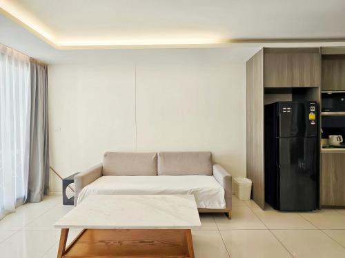 a living room with a couch and a black refrigerator at Circle REIN Sukhumvit 12 Bangkok in Bangkok