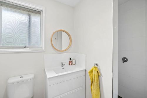 un bagno bianco con lavandino e specchio di 2 Russell a Anglesea