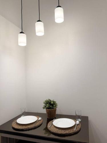two plates on a table with a plant and lights at Stars & Sunsets Sky Views 1br Iguazu Tower in Manila