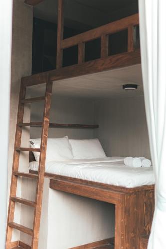 a bunk bed with white sheets and a ladder at A-Lofts Sea Studio 2 Central & Stylish in Dalumpinas Oeste
