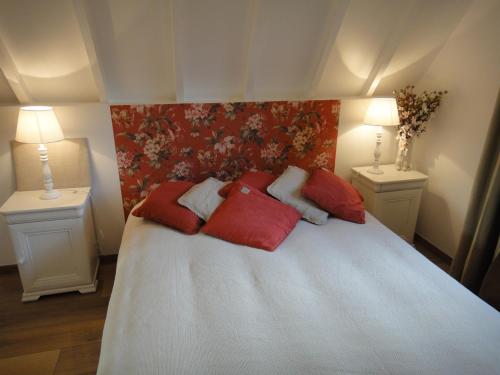 Un dormitorio con una cama con almohadas rojas. en La Petite Chaumière, en Gonneville-sur-Honfleur