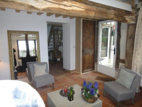 - un salon avec deux chaises et une table fleurie dans l'établissement La Petite Chaumière, à Gonneville-sur-Honfleur