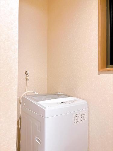 a white washing machine in a corner of a room at Modern New House in Akabane Direct Access to Ikebukuro Shinjuku 新宿池袋赤羽 ## Shuttle, Ticket, Restaurant reservation service ## in Tokyo