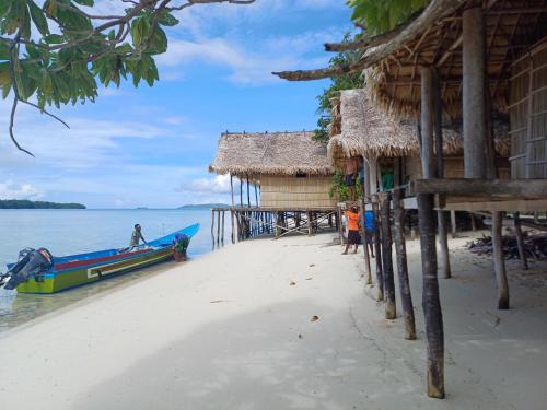 a boat on a beach next to a hut at Yefkabu Homestay Raja Ampat in Waisai