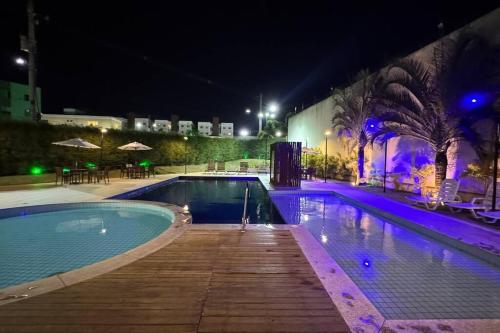 a swimming pool at night with purple lights at Apartamento Térreo Climatizado na Avenida Artêmia Pires Freitas in Feira de Santana