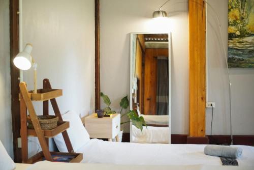 a bedroom with a white bed and a mirror at Hug Bolaven Homestay and Camping in Ban Nongpèn