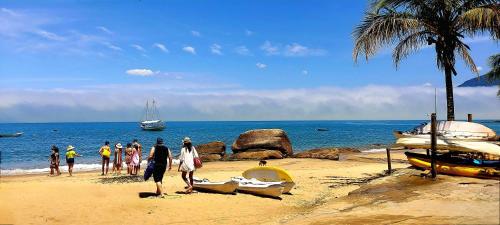 a group of people standing on a beach with boats at Pousada Sobre As Ondas de Picinguaba in Picinguaba