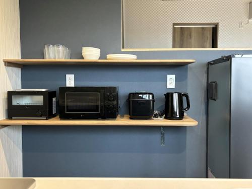 a kitchen with two microwaves and a microwave on a shelf at Orange open-air bath of East Villa-winter only- in Onomichi
