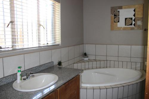 a bathroom with a tub and a sink at Honey Lodge in Klipdrift