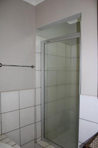 a shower with a glass door in a bathroom at Honey Lodge in Klipdrift