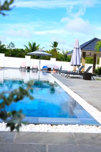 a pool at a resort with chairs and an umbrella at LAM BUNGALOW Resort & Spa in Phu Quoc