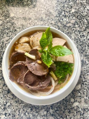 a bowl of soup with meat and greens on a table at LAM BUNGALOW Resort & Spa in Phu Quoc