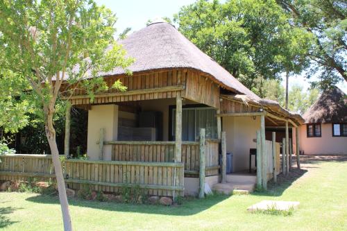 a house with a thatched roof and a yard at Honey Lodge in Klipdrift