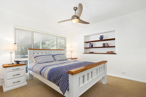 Un dormitorio blanco con una cama y un ventilador de techo. en The Blue Cottage, en Ulladulla
