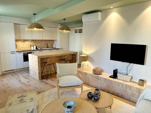 a living room with a tv and a kitchen at La Maison Cavet 5 Appartements de standing au cœur du village in Sanary-sur-Mer
