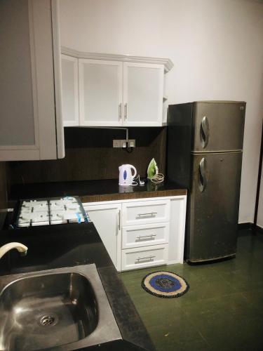 a kitchen with a stainless steel refrigerator and white cabinets at The Moon Lodge in Aluthgama
