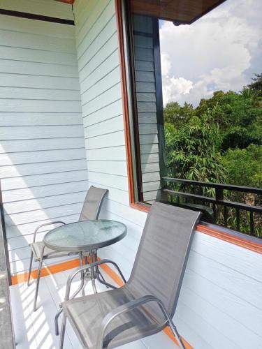 a porch with two chairs and a table and a window at Phangnga Save House - เซฟเฮาส์พังงา in Phangnga