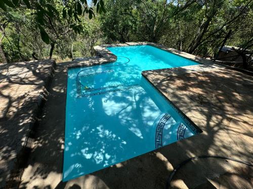 a blue swimming pool with trees in the background at Nectar Game Lodge in Buffelspoort