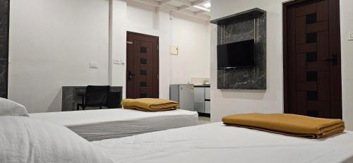 Un dormitorio con dos camas y un televisor en la pared. en MAYPORT HERITREAT, en Alwaye