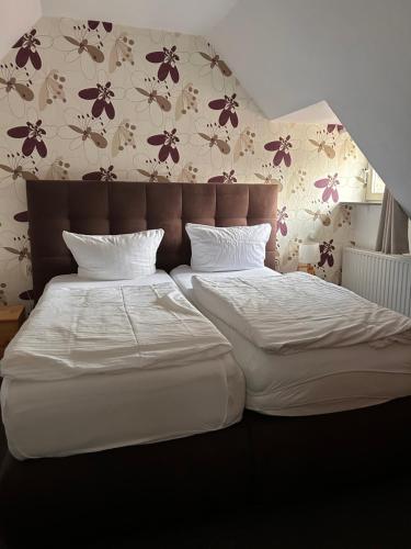 two beds in a bedroom with flowers on the wall at Alte Schlosskurve Hotel & Restaurant in Bad Arolsen