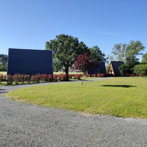 a grassy field with a building and a tree at Tipi Cheyenne des monteaux in Vivy