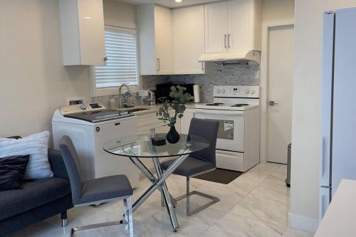 a kitchen with a glass table and a kitchen with white cabinets at Modern Spacious 1BR minutes away from Main St in Vancouver