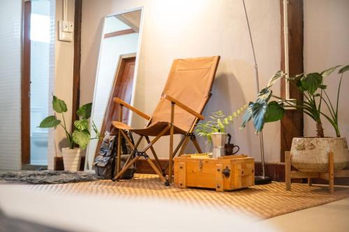 a chair and a suitcase in a room with plants at Hug Bolaven Homestay and Camping in Ban Nongpèn