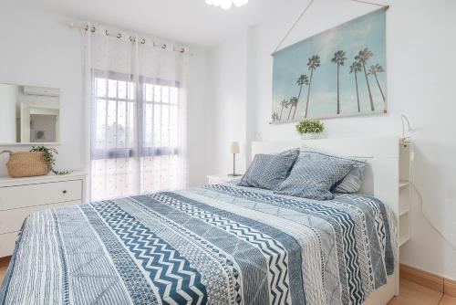 a bedroom with a bed with a blue and white comforter at VERDEMAR 3, PLAYA HONDA in Cabo de Palos