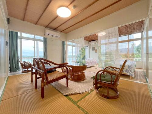 a living room with chairs and a table and windows at MAETAKAYA しまんちゅ in Ishigaki Island