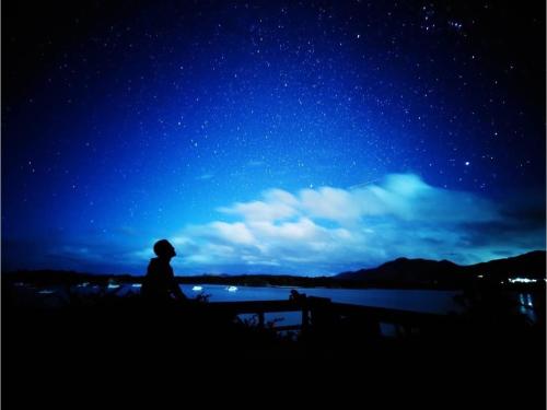 a person sitting in front of a lake at night at MAETAKAYA しまんちゅ in Ishigaki Island