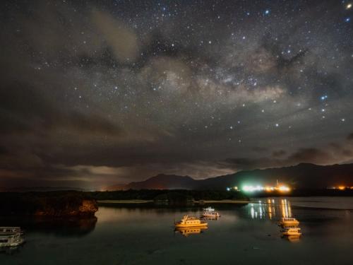 a starry sky with boats on a lake at night at MAETAKAYA しまんちゅ in Ishigaki Island