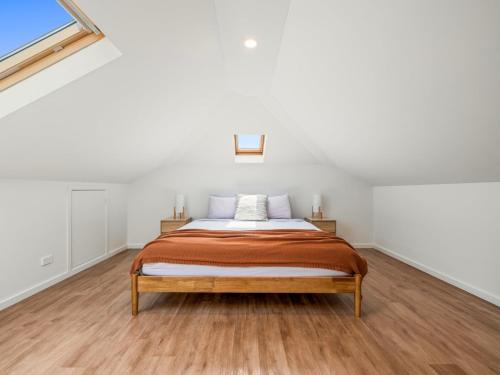 a bed in a white room with a wooden floor at The Mitchell Bondi in Sydney