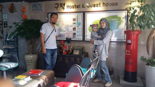 two men and a woman holding a baby in a restaurant at Gudeok Guesthouse in Seogwipo
