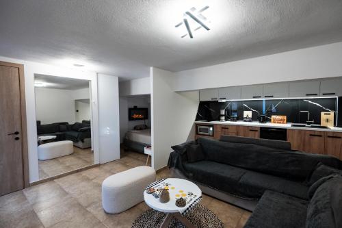 a living room with a black couch and a kitchen at To Bee or not to Bee! in Volos