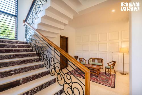 a staircase in a house with a stair railing at StayVista at Imperial Isle 4BHK with FREE BF Luxury Pool Villa in Sohna Delhi in Sohna